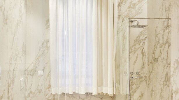 A modern bathroom with a marble wall, a glass shower enclosure, a sink, and a bidet. - Residenza Quartieri Storici  (Florence)