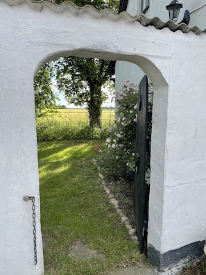 Un bâtiment blanc avec une arche en pierre qui mène à un jardin.