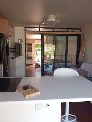 A modern kitchen with a central island, a dining area with a white table and chairs, and a sliding glass door leading to a patio.