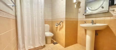 Un baño con inodoro, lavamanos, cortina de ducha, toallero y espejo.