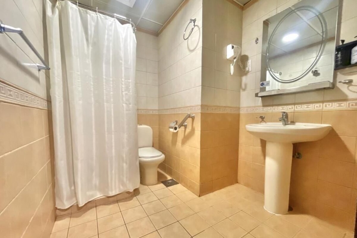 A bathroom with a shower, toilet, sink, and a mirror.