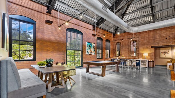 A spacious indoor area with exposed brick walls, large windows, and a pool table. - Historic Loft Retreat With Pool (Pittsburgh)