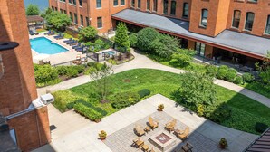 A courtyard with a swimming pool, lounge chairs, and outdoor seating. - Historic Loft Retreat With Pool (Pittsburgh)