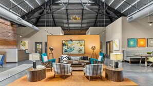 A spacious lobby with a high ceiling, a reception desk, and a seating area with modern furniture. - Historic Loft Retreat With Pool (Pittsburgh)