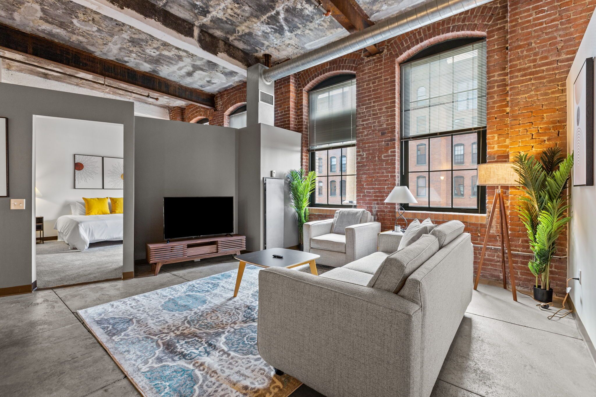 A spacious living room with a large sofa, a flat-screen TV, and a patterned rug.