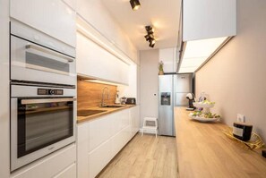 Enjoy cooking in this well-lit kitchen with oven, stainless steel refrigerator, and ample workspace.