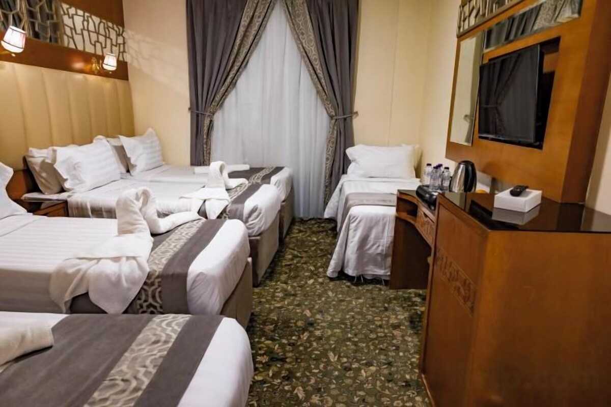 Ein Hotelzimmer mit zwei Betten, einem hölzernen Schminktisch, einem Spiegel und einem Fenster mit Vorhängen.