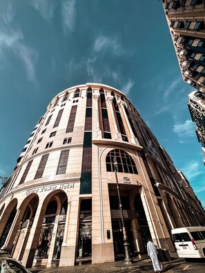 Un hôtel de luxe à la façade incurvée, doté de grandes fenêtres en arc de cercle et d’une entrée imposante.