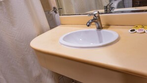 Een wastafel met een spiegel erboven, een kraan en een toiletrolhouder.