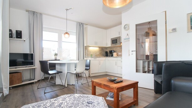 A modern apartment with a living room, dining area, kitchen, and a small balcony.
