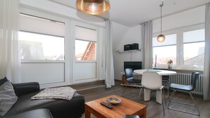 A modern living room with a sofa, a coffee table, and a dining area with chairs and a table.