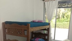 A bunk bed with a wooden headboard, a single bed below, a fan, and a window with curtains. - Casa de Verano Mediterranea (Carmen de Apicalá)