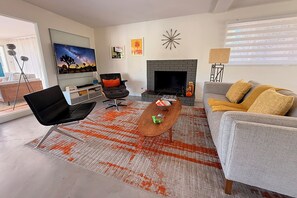 Ein Wohnzimmer mit Kamin, einer Couch, einem Couchtisch und einem Fernseher.