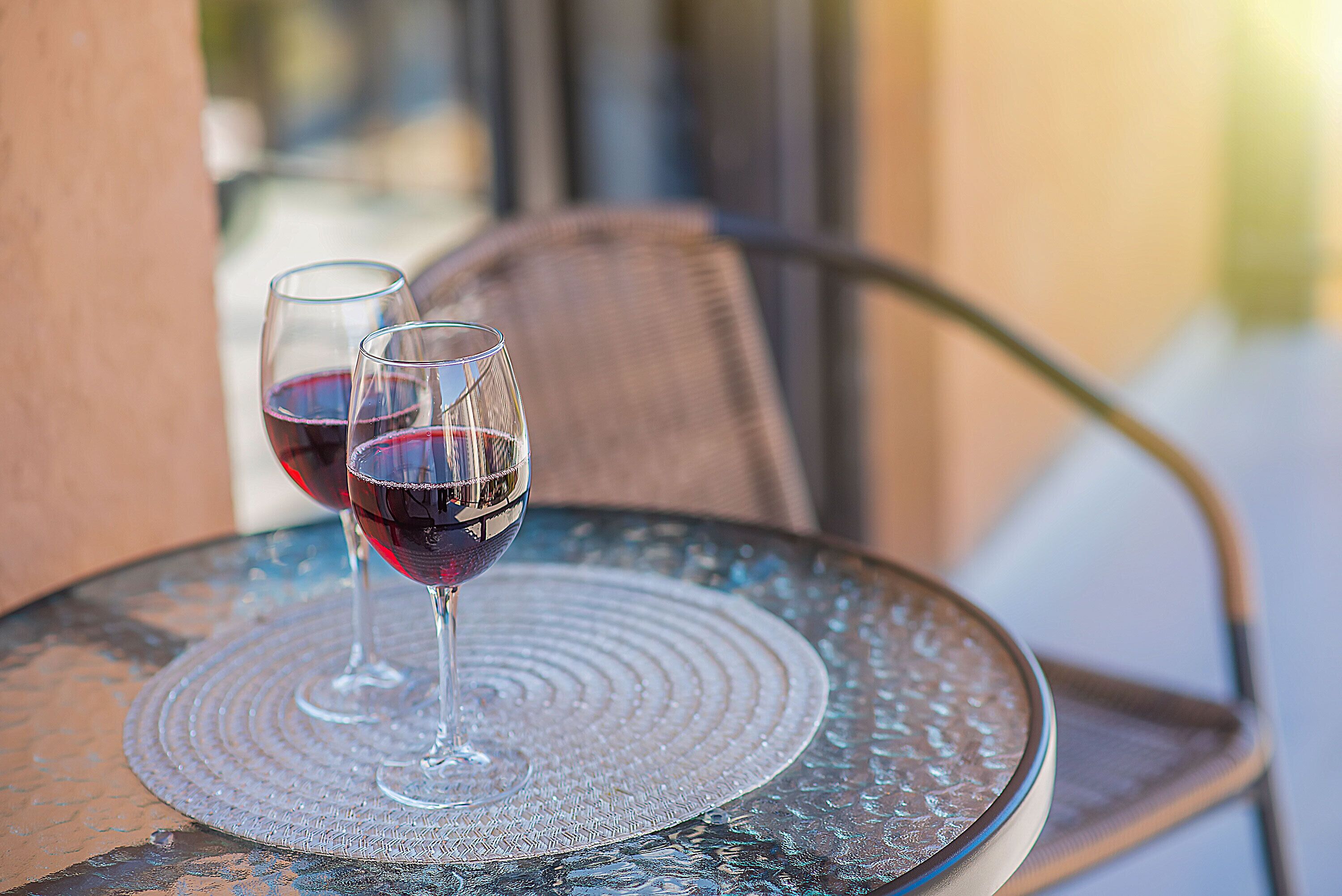 Deux verres à vin sont posés sur une table en verre, sur laquelle se trouve un tapis texturé.