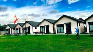 A row of modern, single-story buildings with large windows and a grassy lawn in front. - Cozy holiday homes, close to the lake (Lazy)
