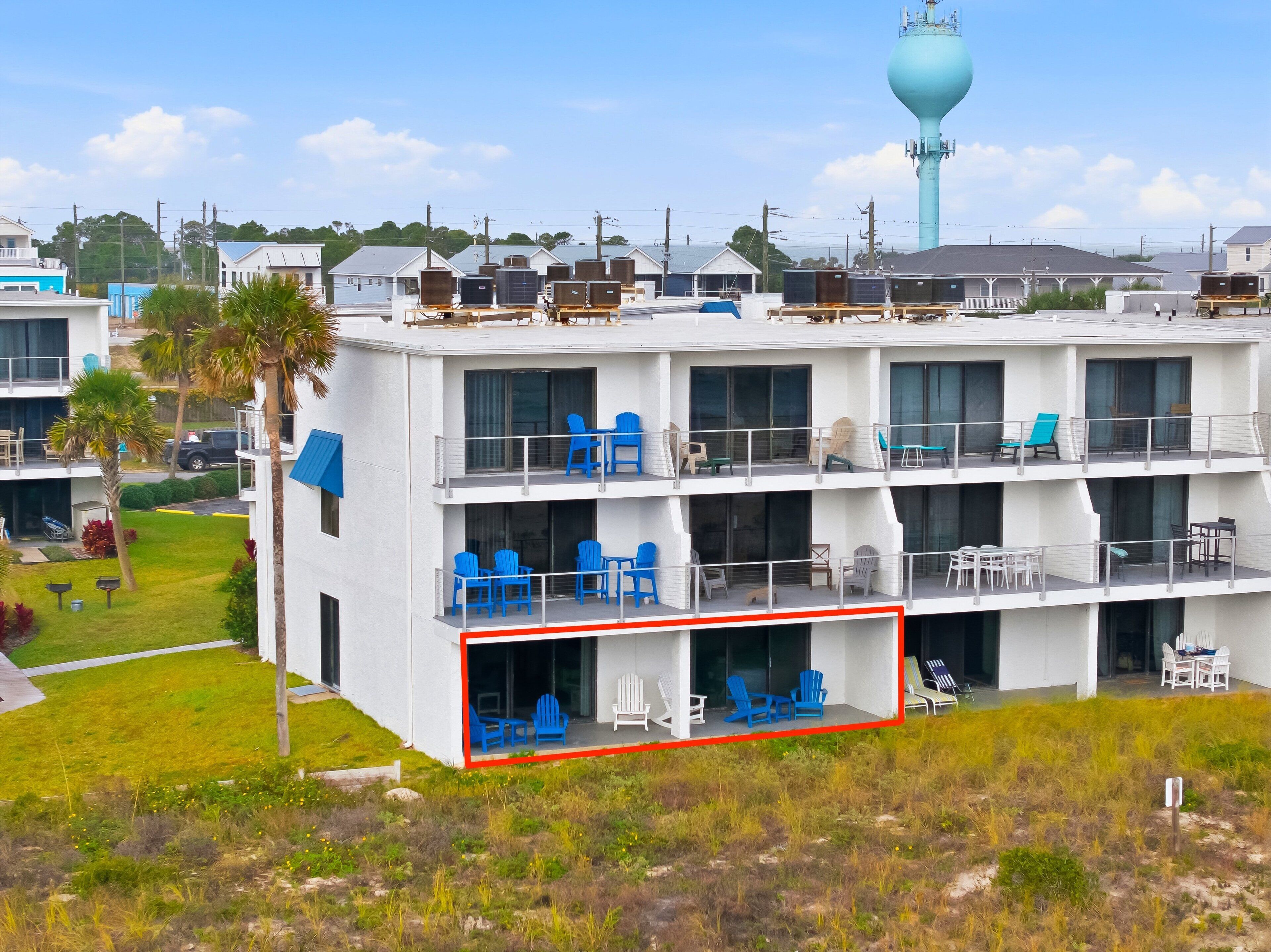 A multi-story hotel with balconies, outdoor seating, and a water tower in the background.
