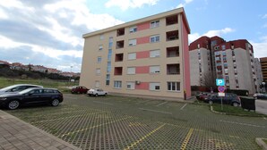 A multi-story residential building with a parking area in front. - Apartment Mladen (Pula)