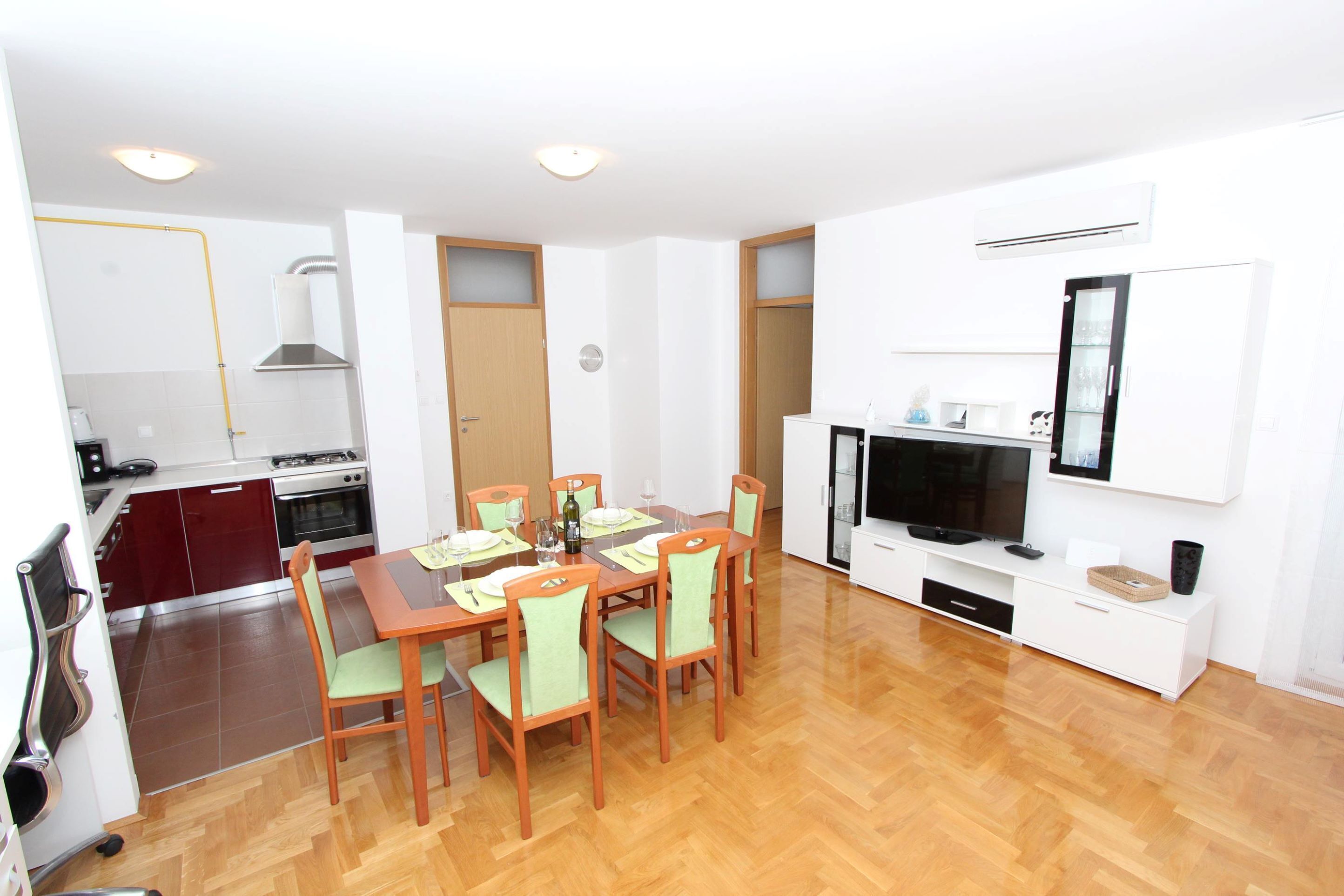 A compact living space with a dining area, kitchenette, and a TV.