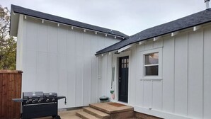 A house with a black grill in the backyard, a small front door, and a window. - Blanche's Bungalow (Graham)