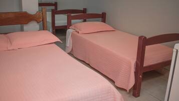A room with two wooden beds, each with a pink quilted bedspread and matching pillows.
