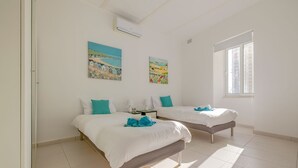 A hotel room with two beds, a window, and two paintings on the wall. - Contemporary Retreat in Prime Sliema Area (Sliema)