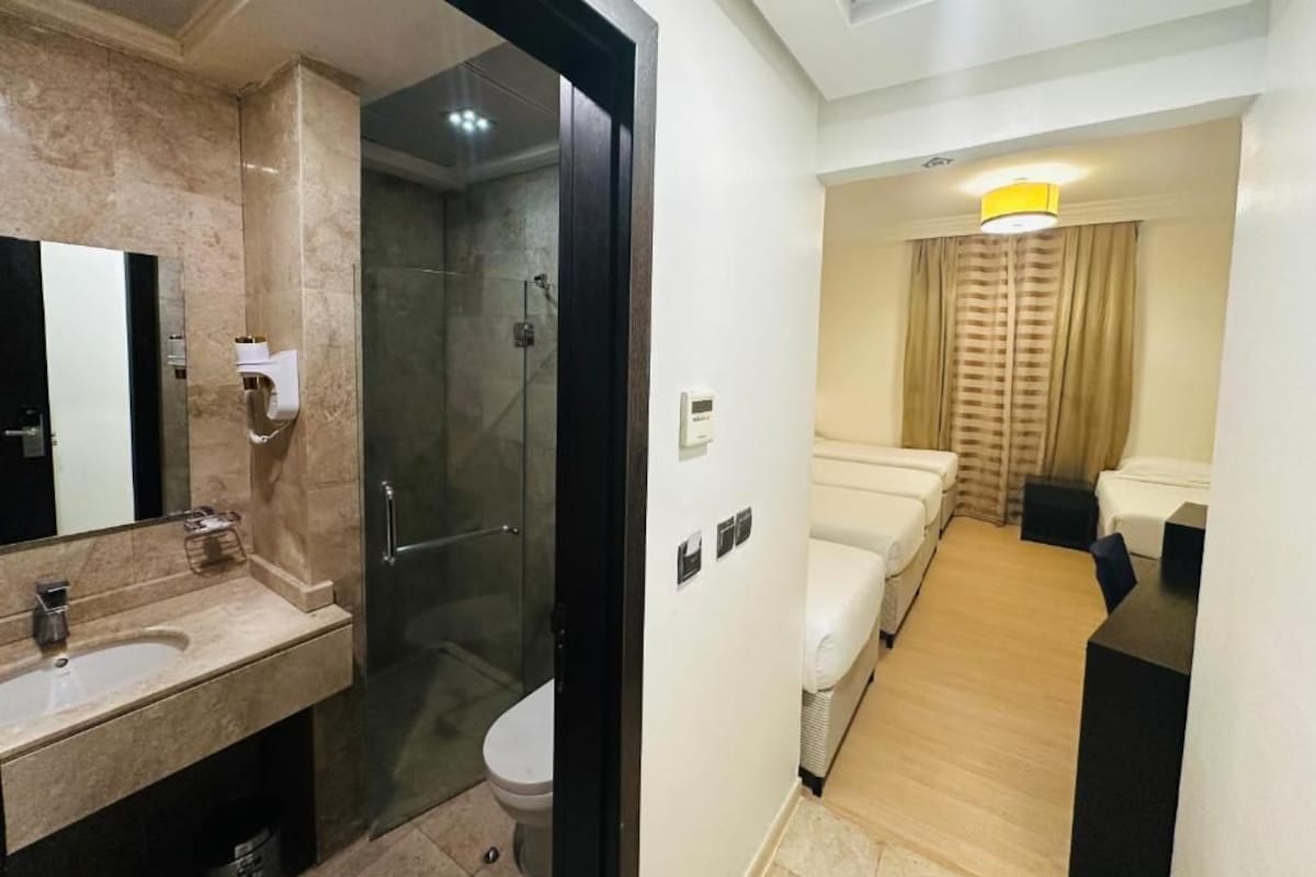 Un baño de hotel con un lavamanos de mármol, ducha con cerramiento de vidrio y un inodoro.