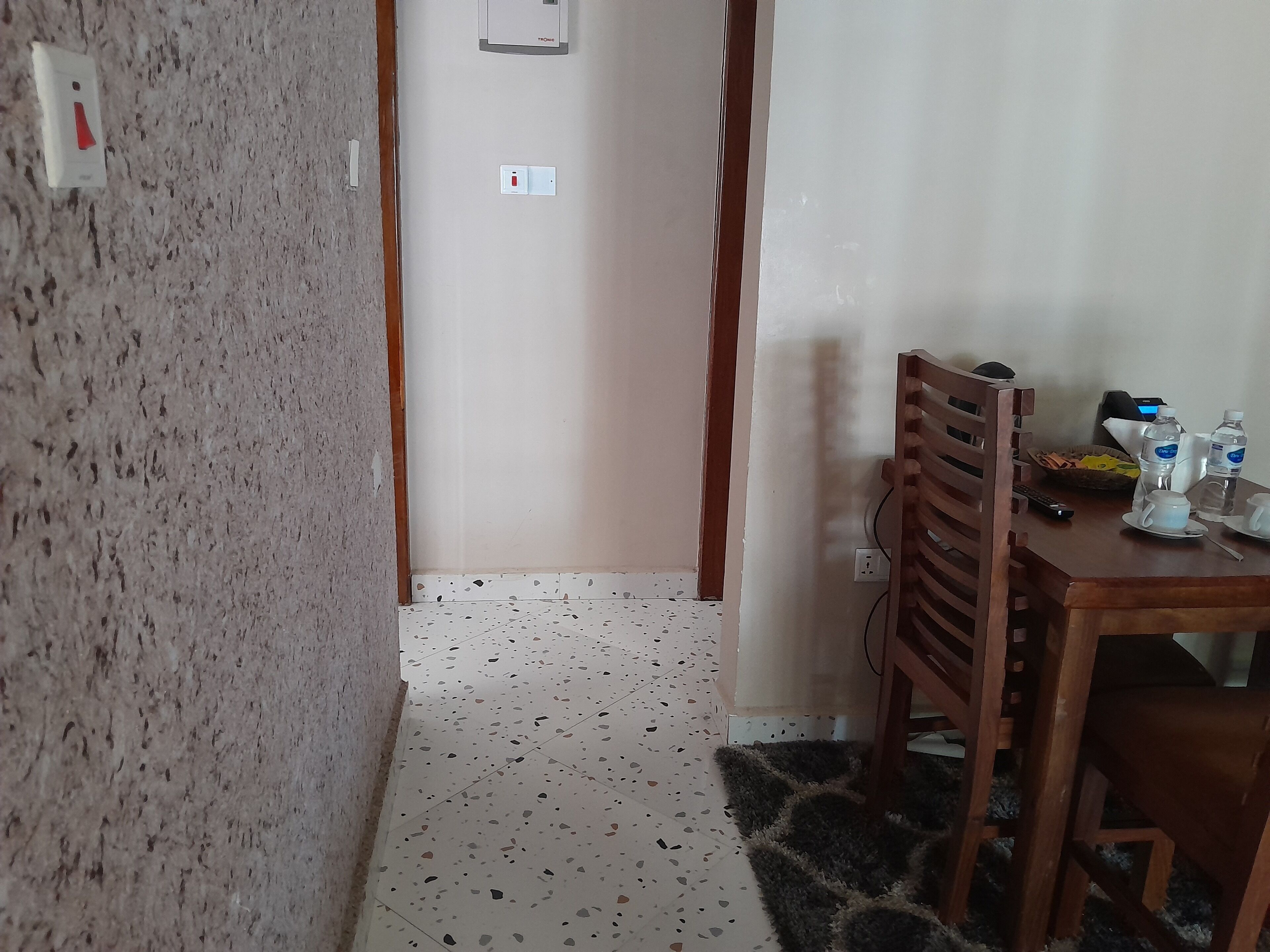 Una habitación con kitchenette, un comedor con mesa y sillas, y suelo estampado.