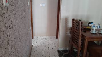 Una habitación con kitchenette, un comedor con mesa y sillas, y suelo estampado.