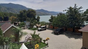 Ein Wohngebiet mit einem gepflasterten Innenhof, geparkten Fahrzeugen und Blick auf einen See mit Bergen im Hintergrund.