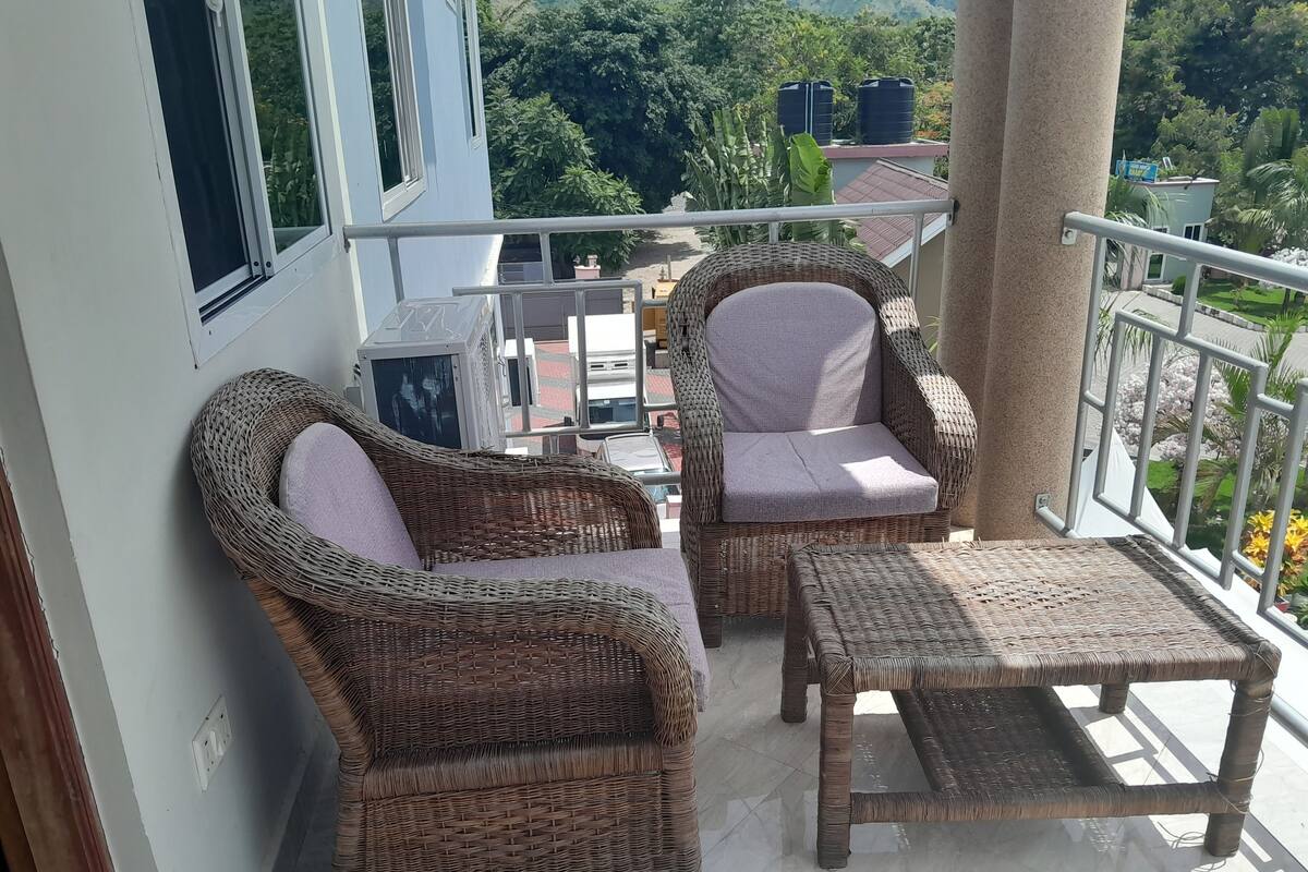 Ein Balkon mit Korbmöbeln, darunter zwei Stühle und ein kleiner Tisch.