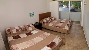Quarto de hotel com duas camas, uma mesinha de cabeceira, um telefone e uma porta de vidro deslizante para uma varanda.