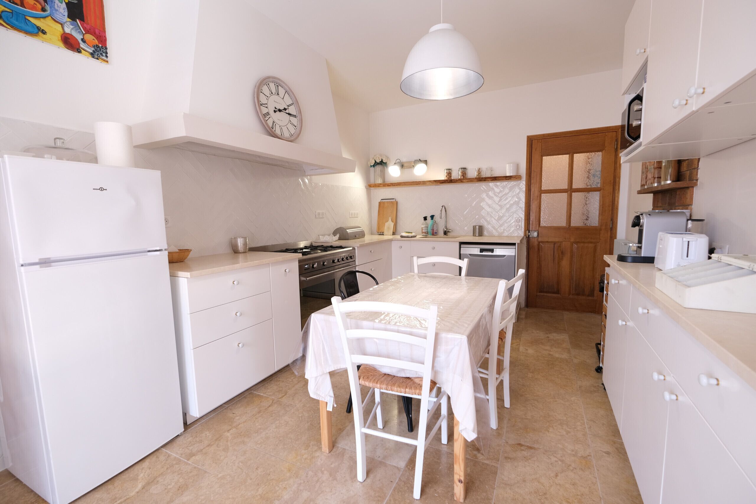 A compact kitchen with white cabinetry, a dining table with chairs, a stove, and a microwave.
