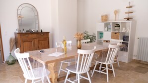 A dining area with a wooden table, white chairs, a mirror, and a white cabinet with shelves. - Vacation rental house with pool MOURIES LS1-434 (Mouriès)