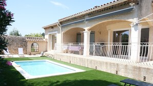 A poolside area with a rectangular pool, a covered patio with white railings, and a stone wall. - Vacation rental house with pool MOURIES LS1-434 (Mouriès)