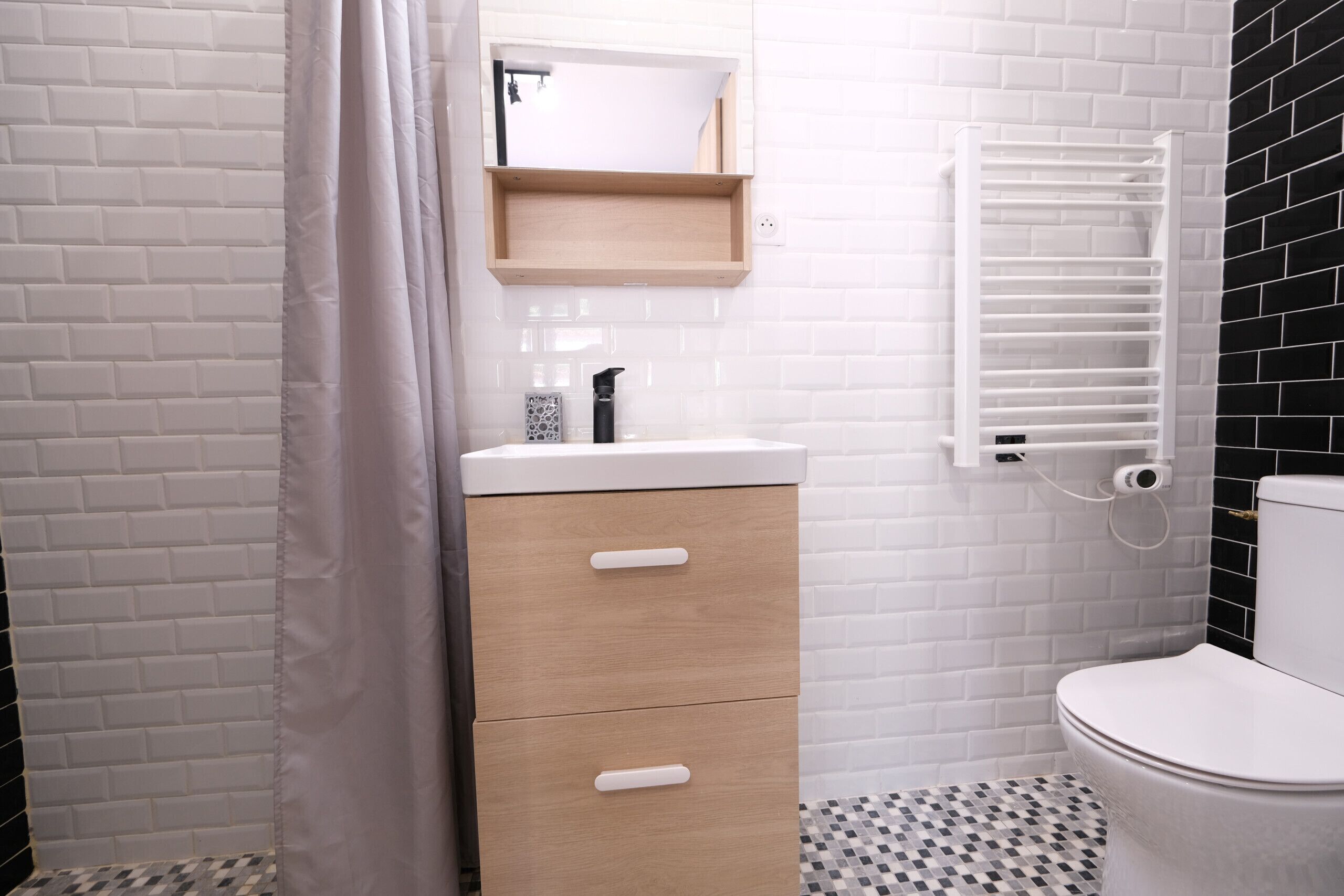 Une salle de bain avec un lavabo blanc, un meuble en bois et des toilettes blanches.