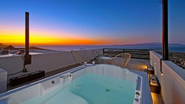 Terraza en la azotea con jacuzzi, zona de estar y vistas a la puesta de sol sobre el océano.