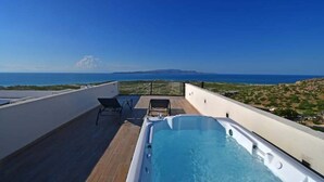 Zona de piscina en la azotea con vistas despejadas al mar y colinas lejanas.