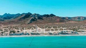 Un paisaje costero con montañas al fondo y una zona de playa con edificaciones.