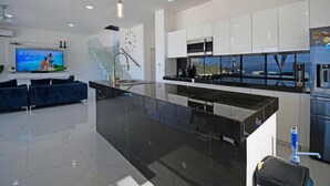 Una cocina moderna con armarios blancos, encimera negra y horno empotrado.