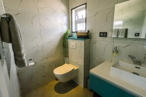 A bathroom with a toilet, sink, and mirror. - Pearl Villa (Grand-Baie)