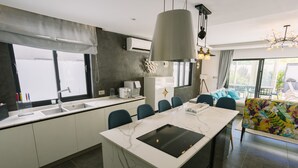 A modern kitchen with a central island, built-in appliances, and a dining area with chairs. - Pearl Villa (Grand-Baie)