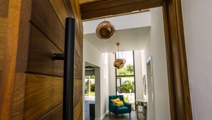 A modern interior with a wooden door, a teal armchair, and pendant lighting. - Pearl Villa (Grand-Baie)
