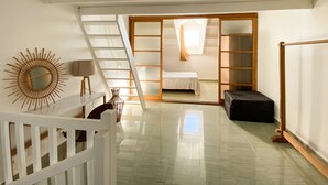 A spacious room with a staircase leading to a bedroom. - Appart Standing vue mer & Marina (Pointe-à-Pitre)