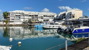 A marina with several boats docked, a wooden dock, and a building with balconies and a sign that reads "Seaberry." - Appart Standing vue mer & Marina (Pointe-à-Pitre)