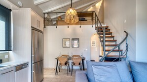 A modern kitchen with a built-in refrigerator, dining area with wicker chairs, a staircase, and a blue sofa. - Deluxe Seaside Condo for 6 (Kantia)