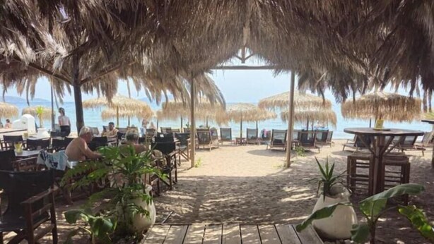 A beachside restaurant with outdoor seating, thatched umbrellas, and a wooden deck leading to the beach. - Deluxe Seaside Condo for 6 (Kantia)