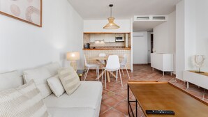 Una sala de estar con sofá, una mesa de comedor y una cocina al fondo.