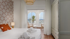 Una habitación de hotel con una cama grande, un balcón con vistas al mar y un armario.