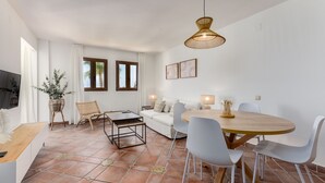 Una sala moderna con sofá, mesa de comedor, sillas y televisor.