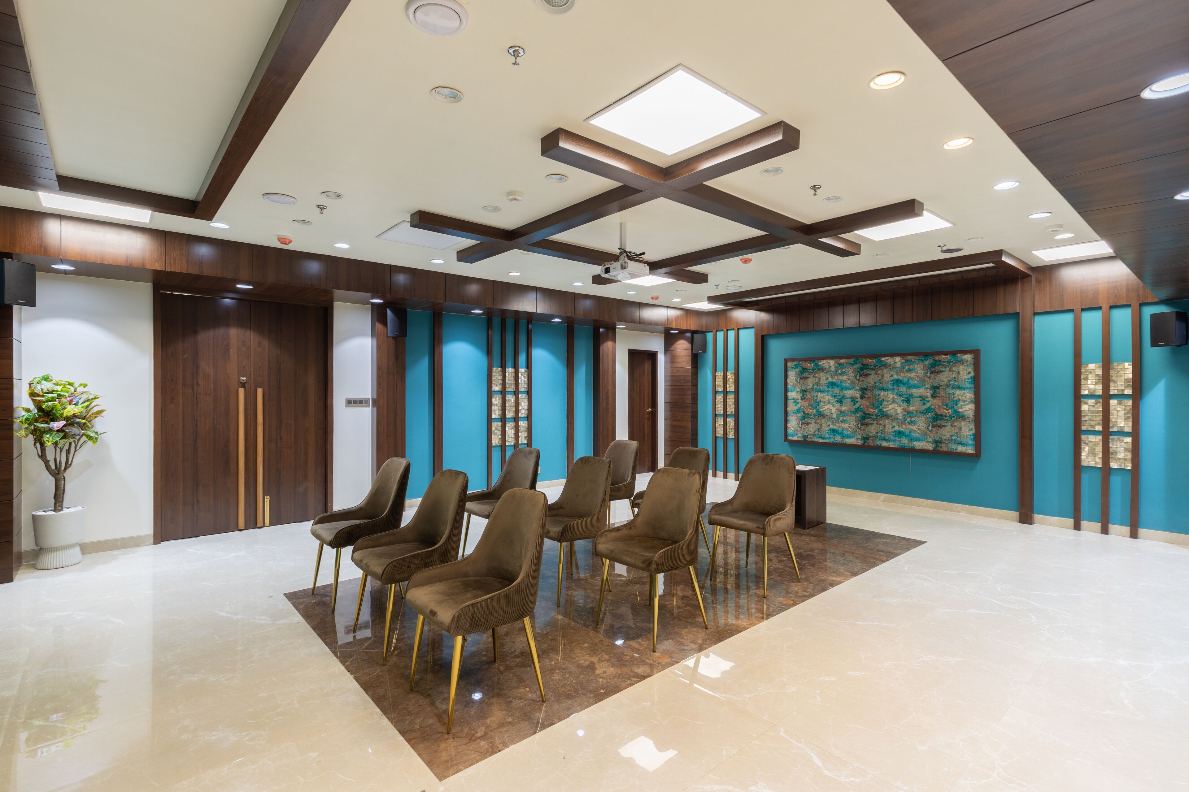 A spacious lobby with a high ceiling, recessed lighting, and a large abstract painting on the wall.